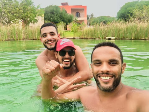 Marouane et deux amis souriants dans l'eau, un jour d'été